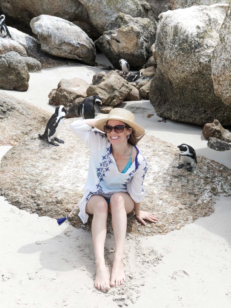 A girl sitting on a rock near penguins.