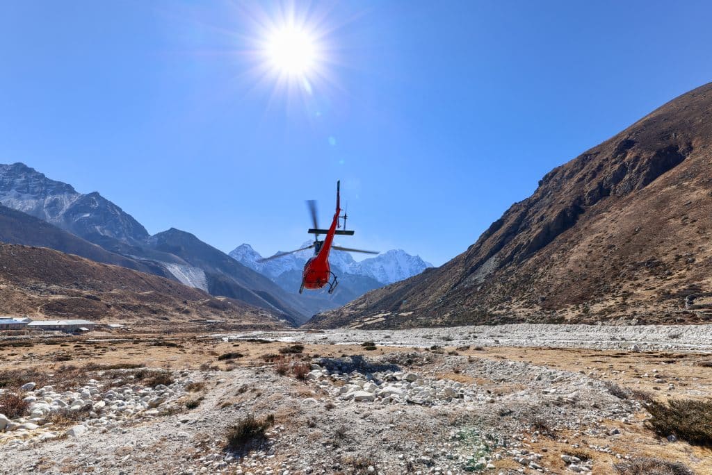 A helicopter flying over a riverbed near Mount Everest Base Camp.