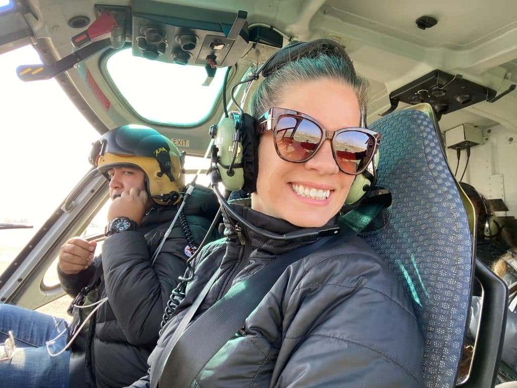 A girl smiling in the front of a helicopter.