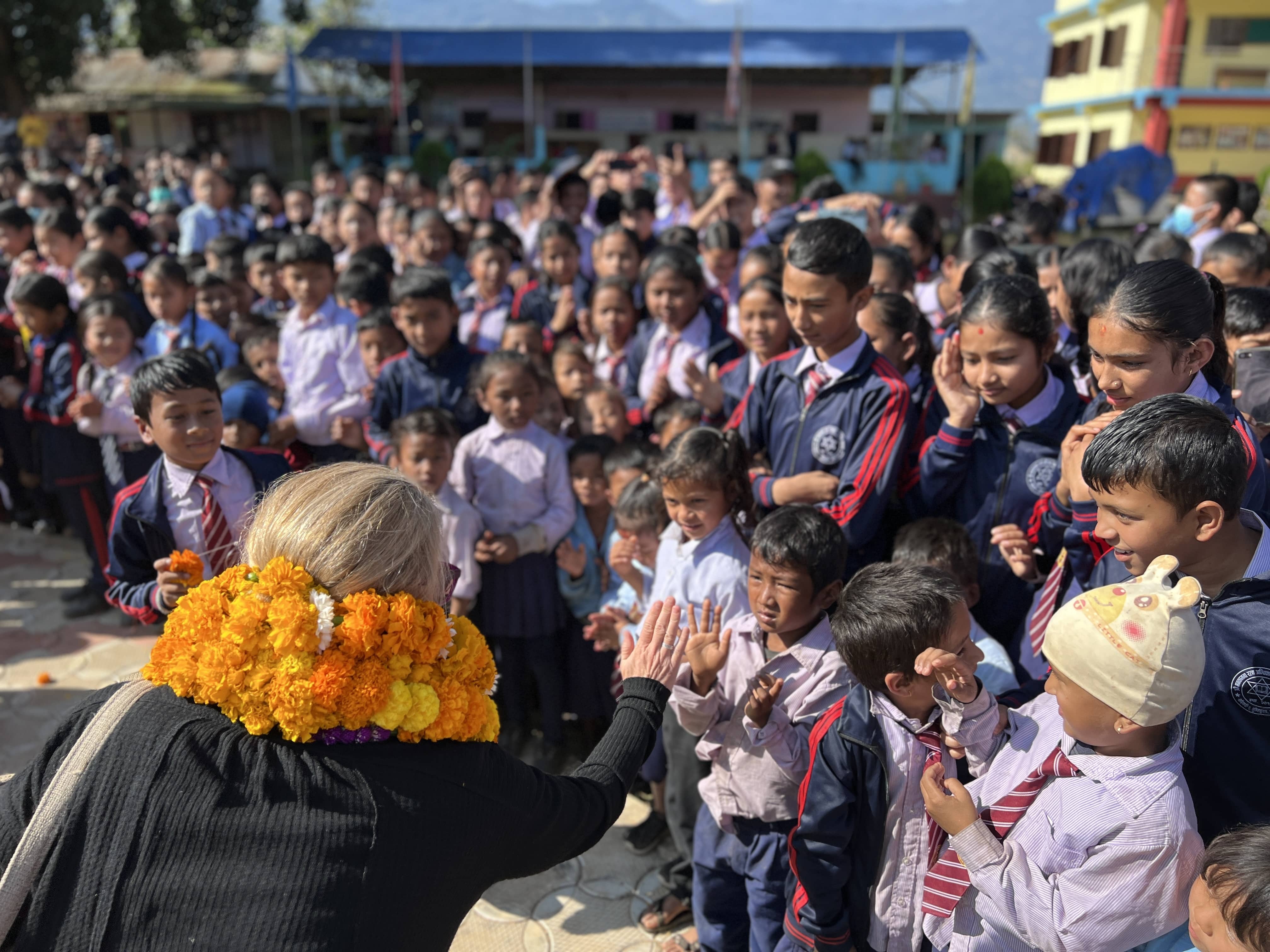 A woman waving at kids welcoming her to their school.