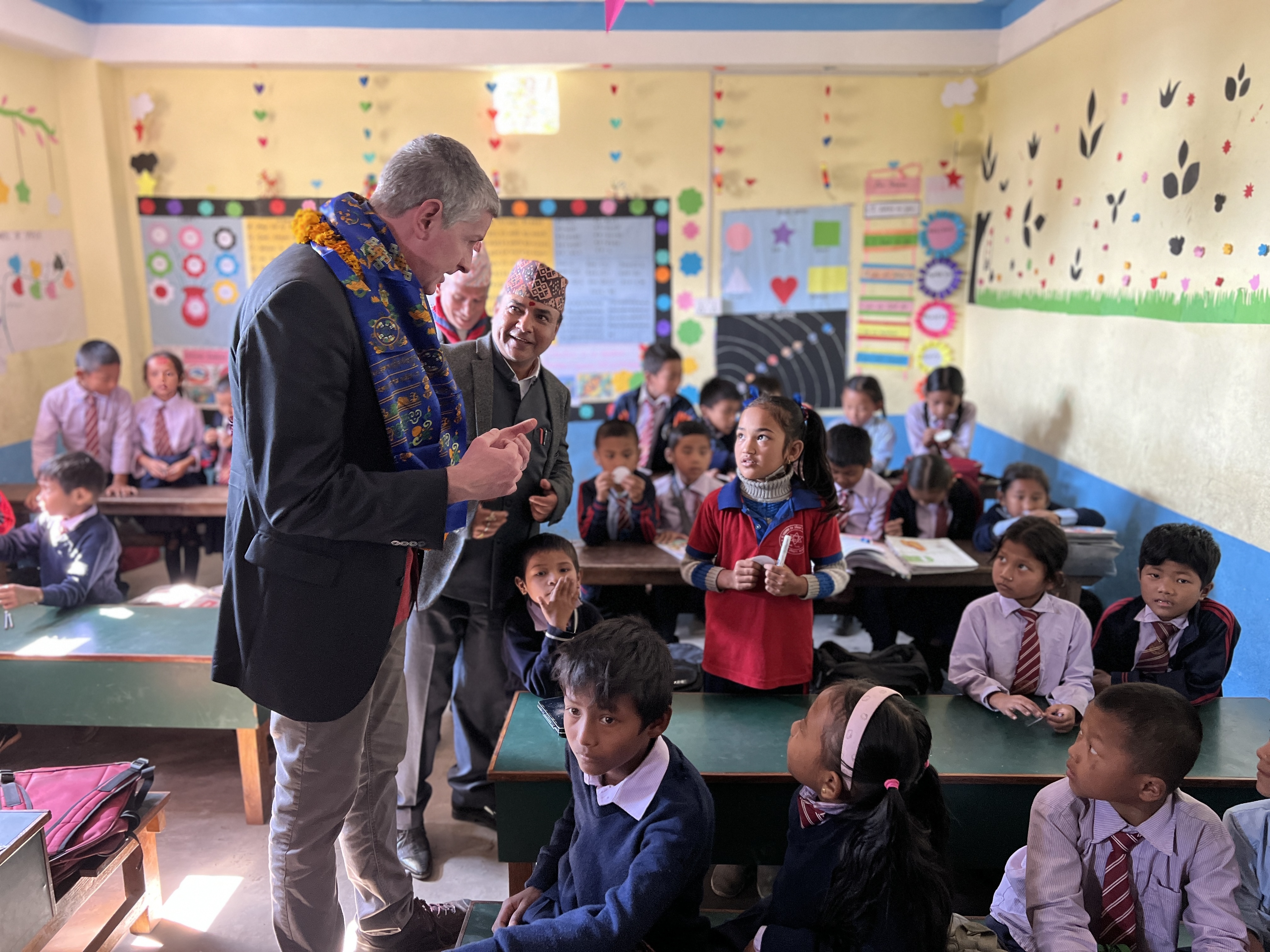 The mayor of a town in Colorado speaking with a little girl in a classroom in Khandbari, Nepal.