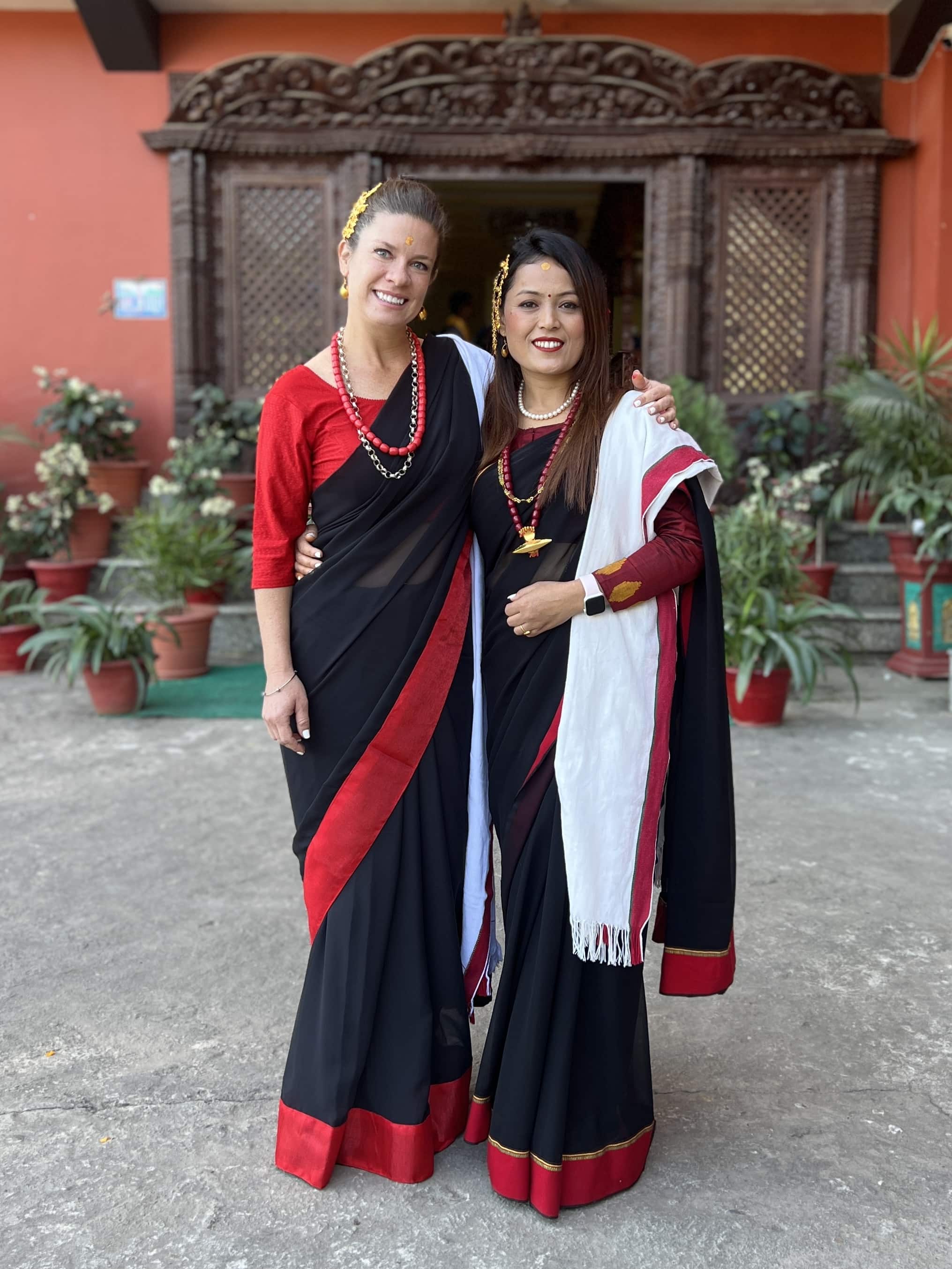 Two young ladies wearing black and red sarees.