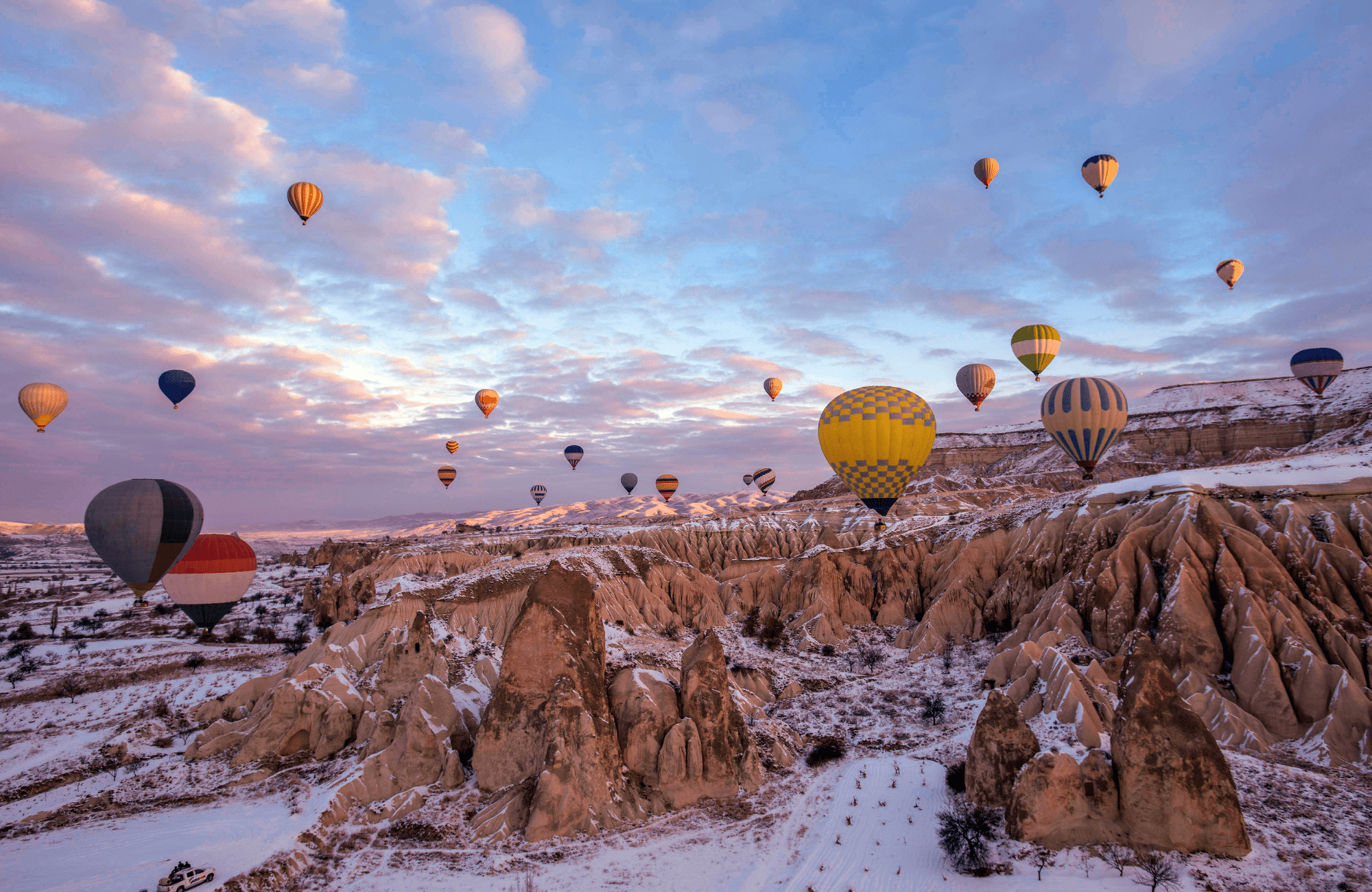 Hot air balloons flying over a winter landscape in Cappadocia.