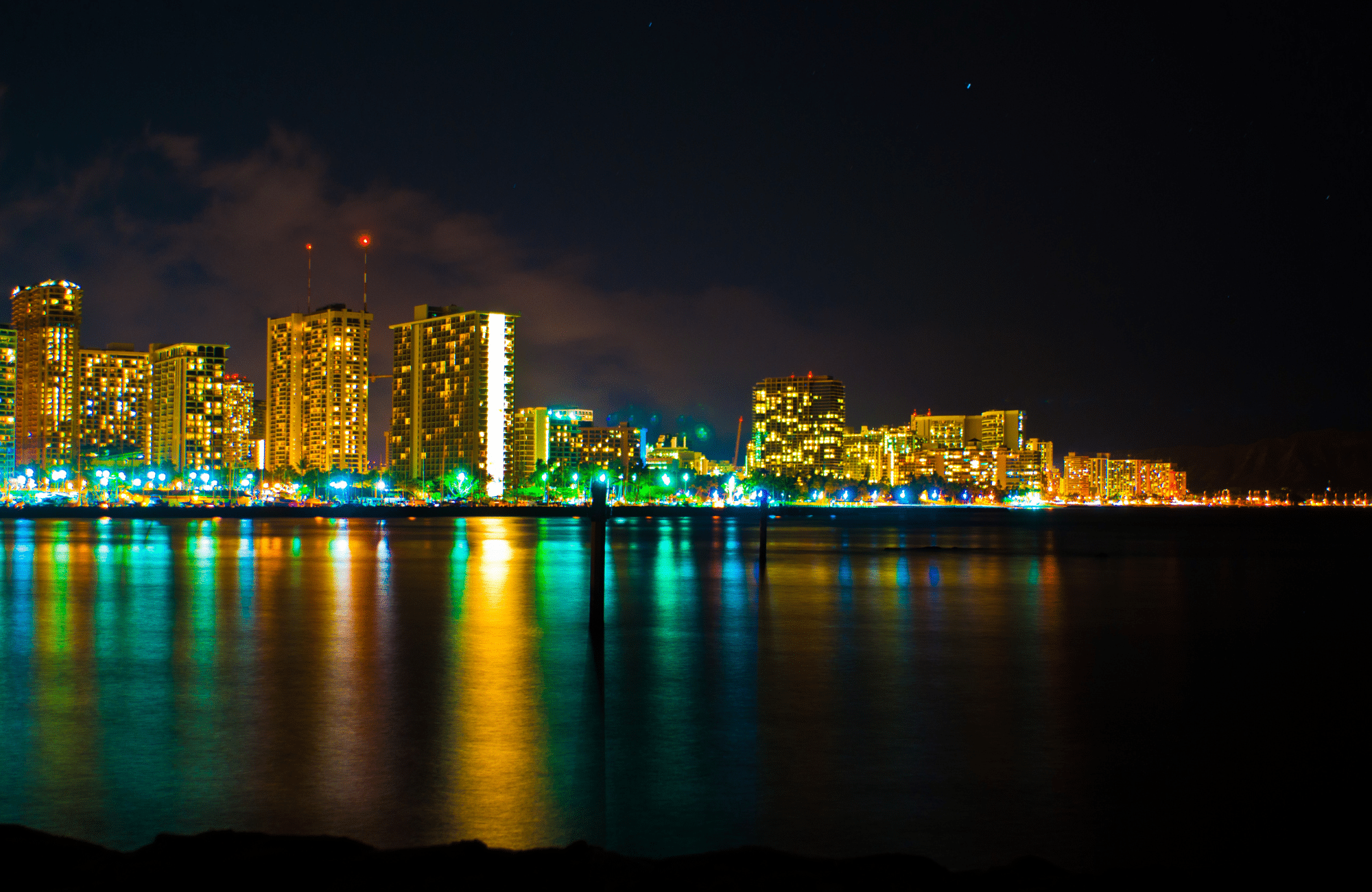 A colorful metro skyline with reflections on the water at night.
