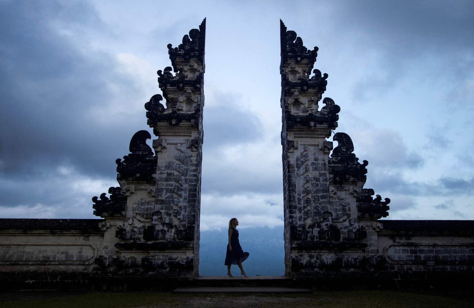 The silhouette of a girl in a dress at the Heaven's Gate temple entrance in Bali at sunrise.