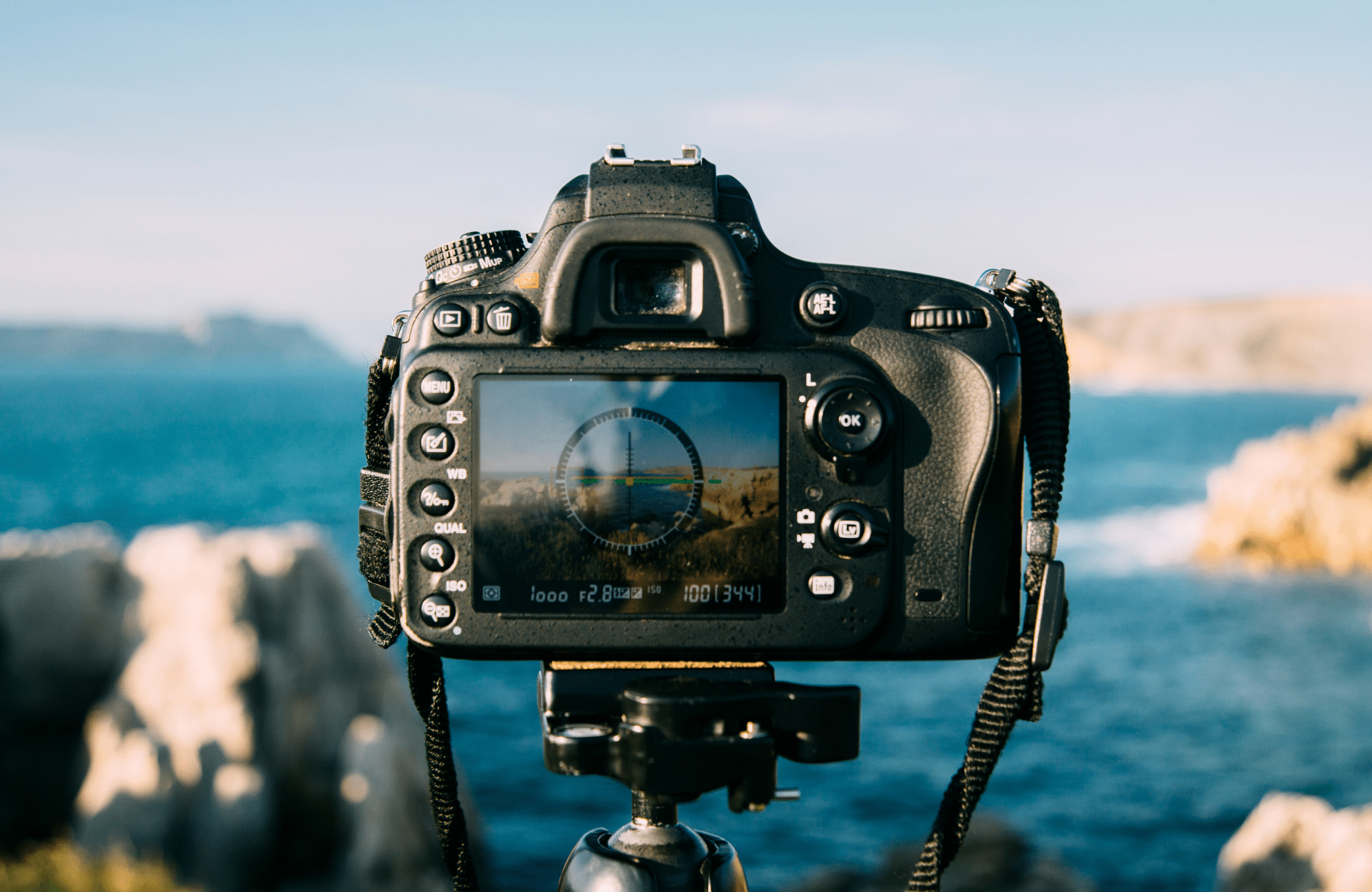 A DSLR Camera in front of an ocean scene.