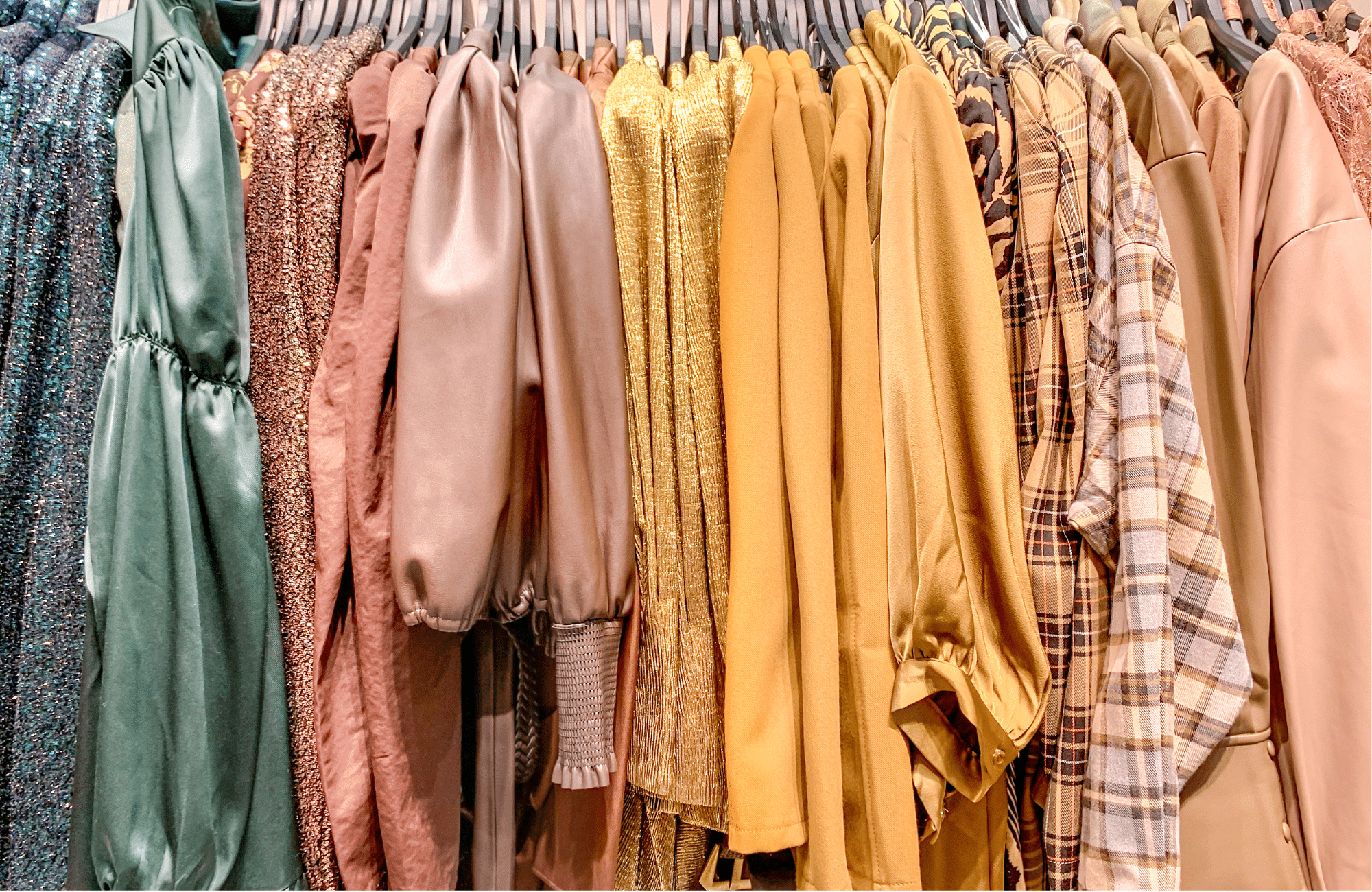 Shirts hung on hangers in rainbow order from green to pink to yellow.
