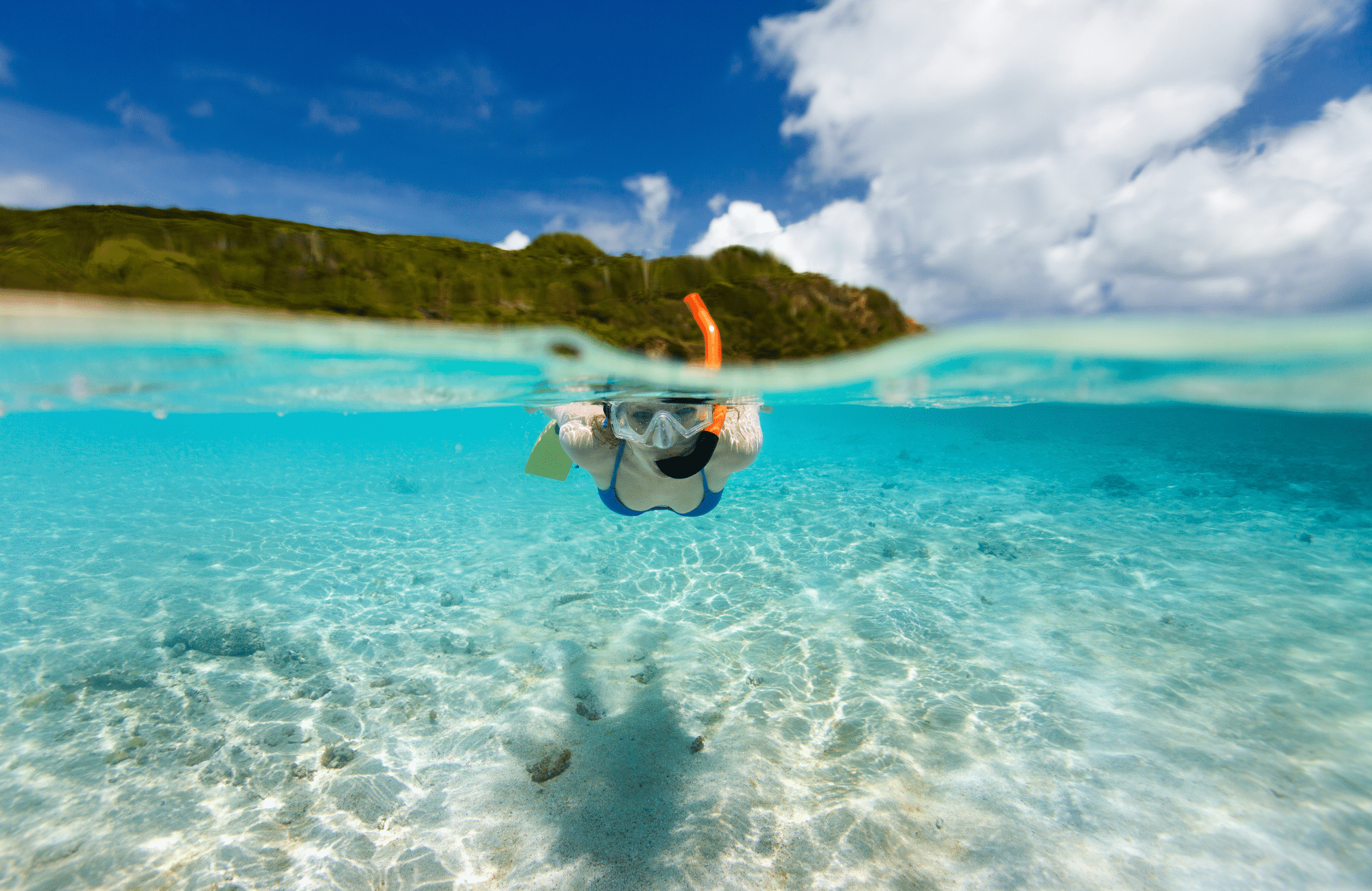 Woman snorkeling in the ocean with bright turquoise waters.