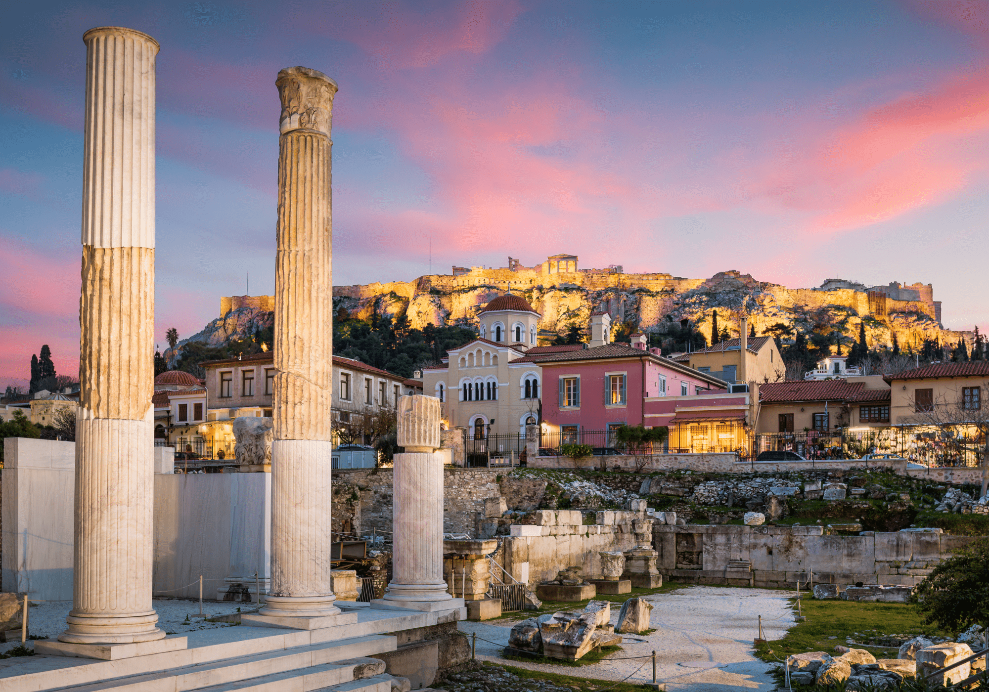 Ancient temples and the city of Athens at sunset.