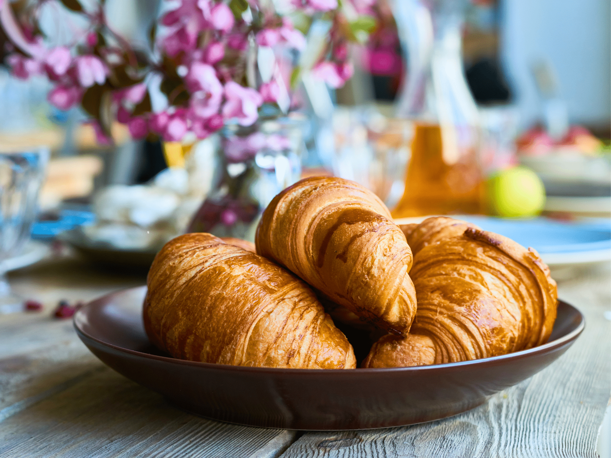 Croissants on a plate with purple flowers in the background.