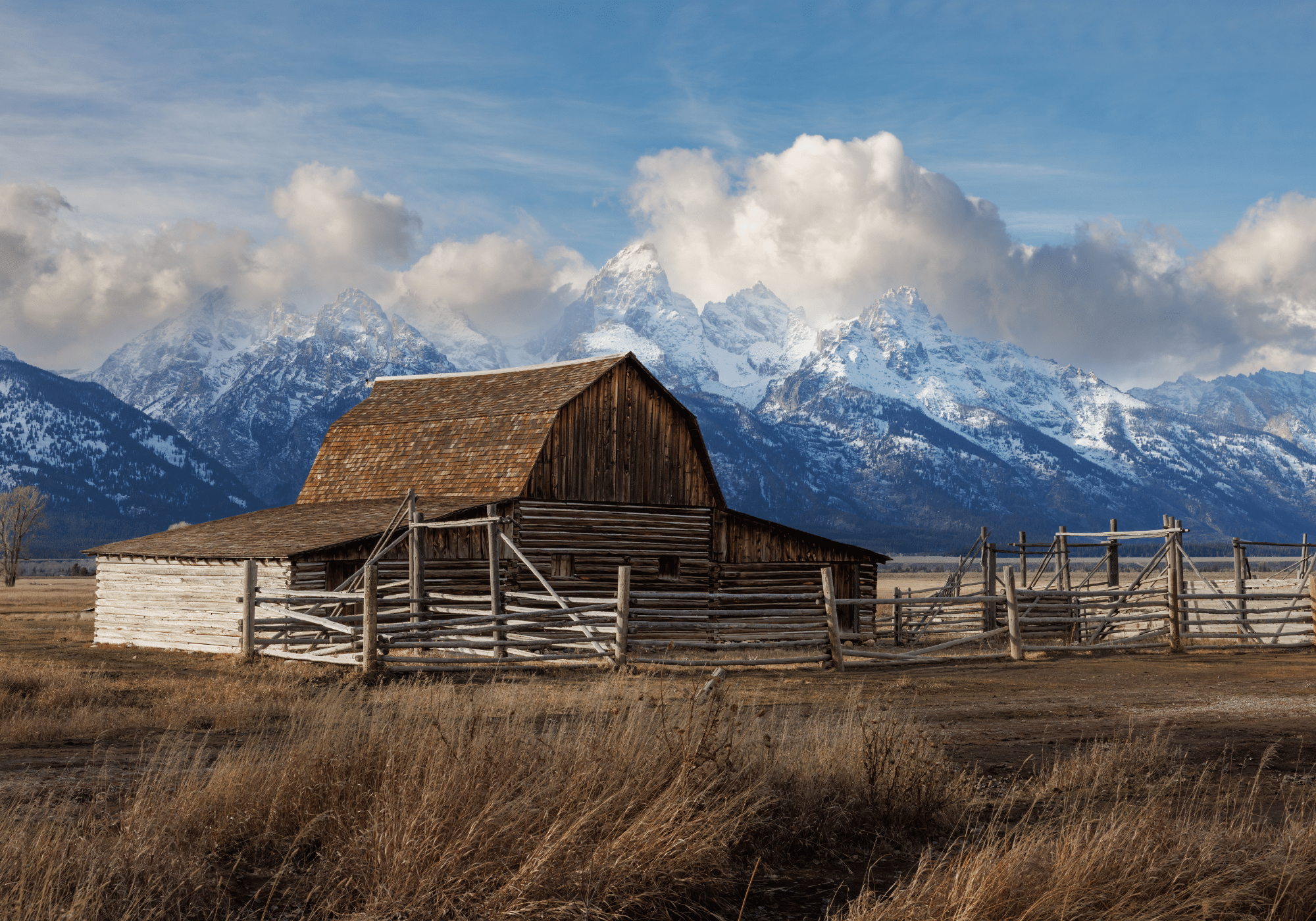 An old wooden bard with the Grand Tetons in the background.