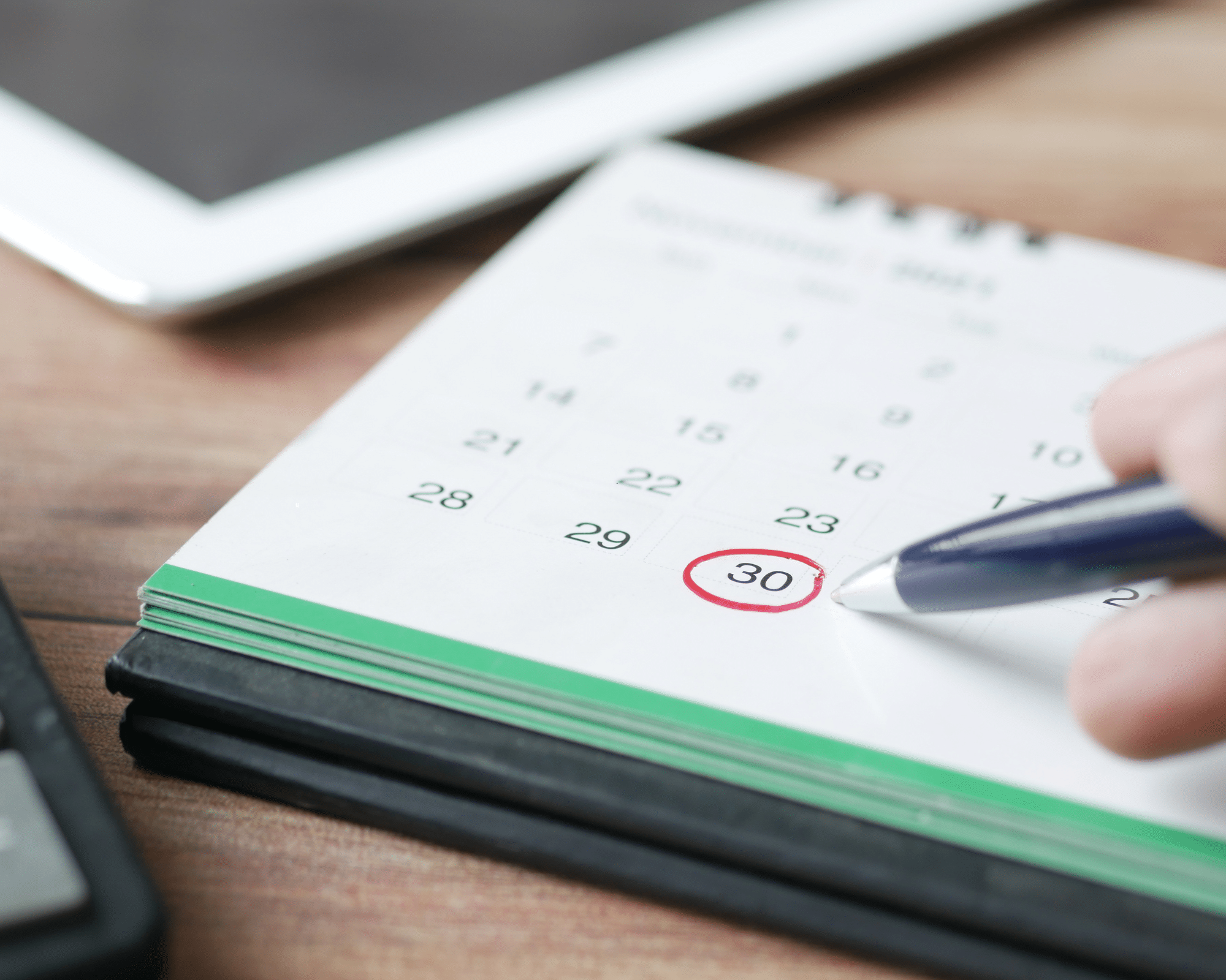 A desl calendar with a pen drawing a red circle around a date.