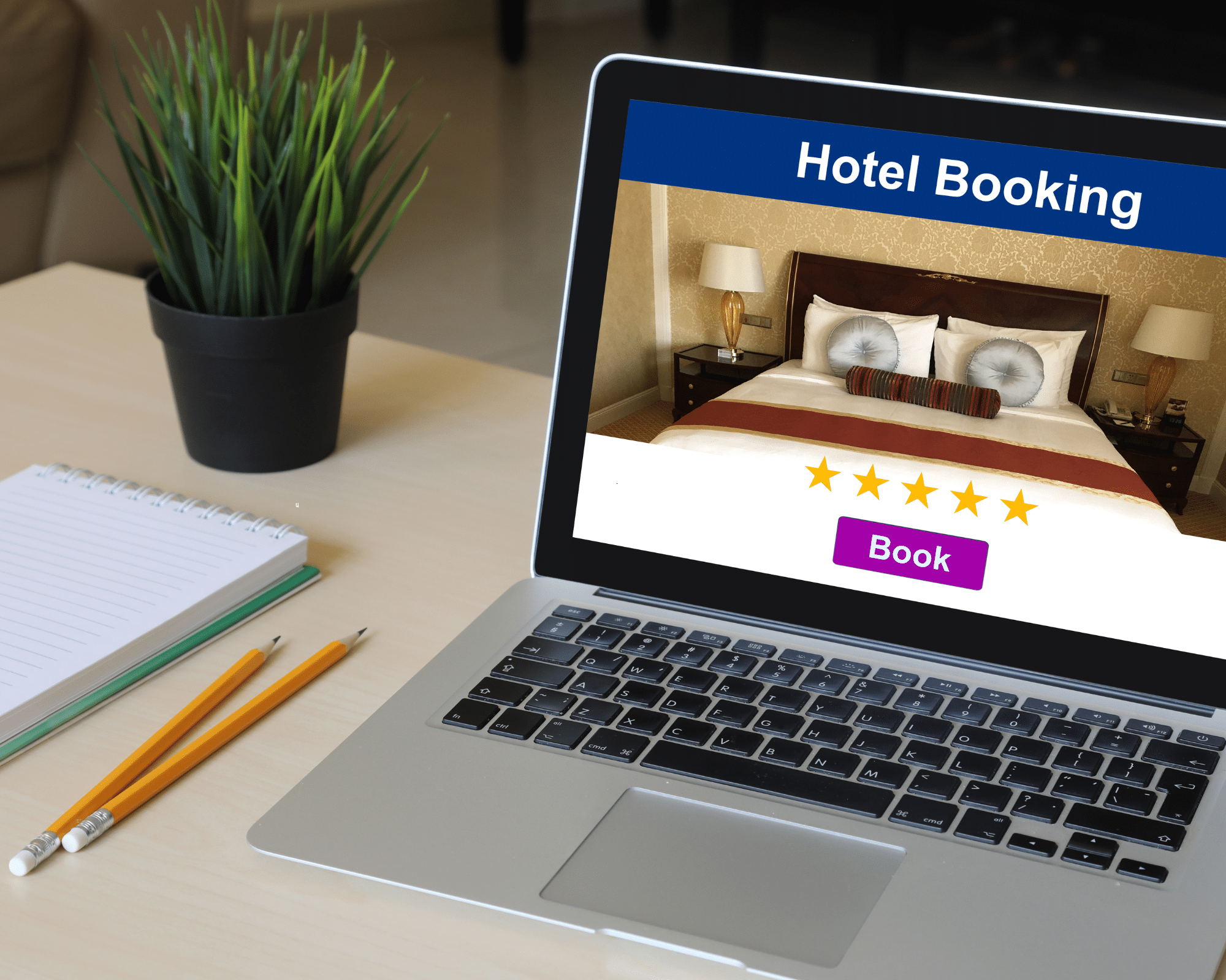 A computer opened to a hotel booking website with pencils and a pad of paper next to it.