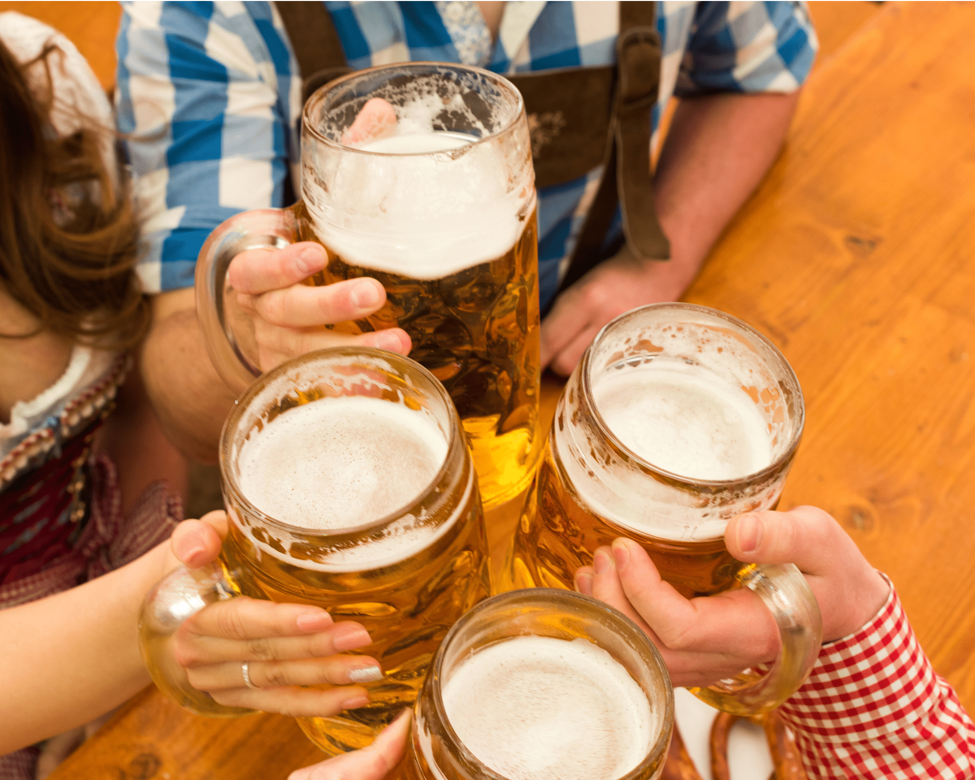 People in traditionall german outfits cheersing four large beers.